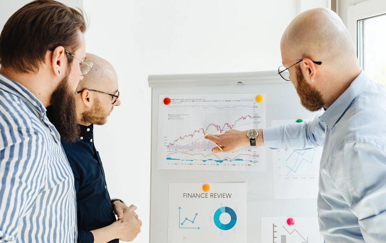three men reviewing charts on a whiteboard